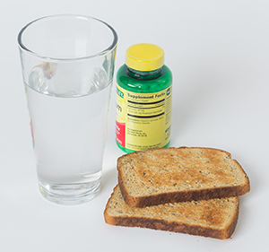 Pan tostado, vaso de agua y dos pastillas.